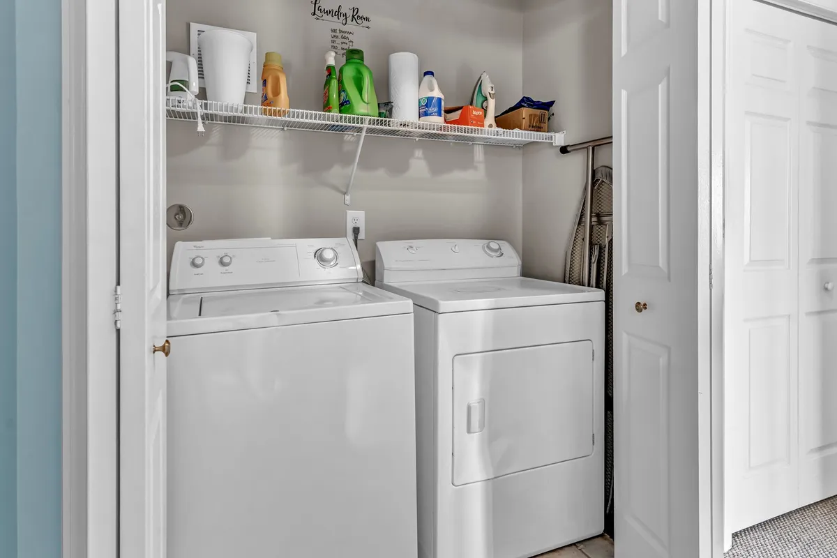 A tidy laundry nook with a full-sized washer and dryer, a shelf stocked with cleaning supplies, and efficient organization. The space, though compact, hints at convenience for keeping clothes and beachwear fresh during longer stays.