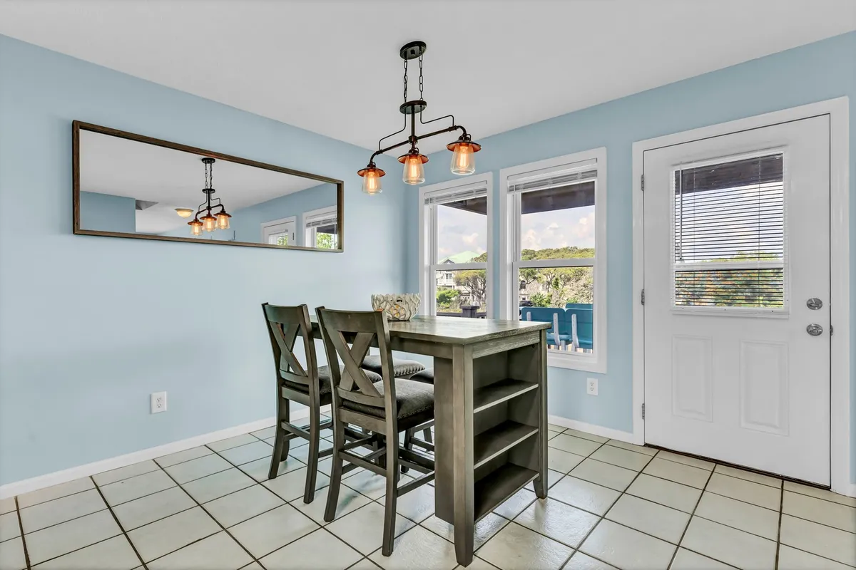 A bright, open dining area with a large table, elegant chandelier, and wide windows letting in plenty of daylight. The setting is ideal for family meals, morning coffee, or celebrating special occasions with loved ones.