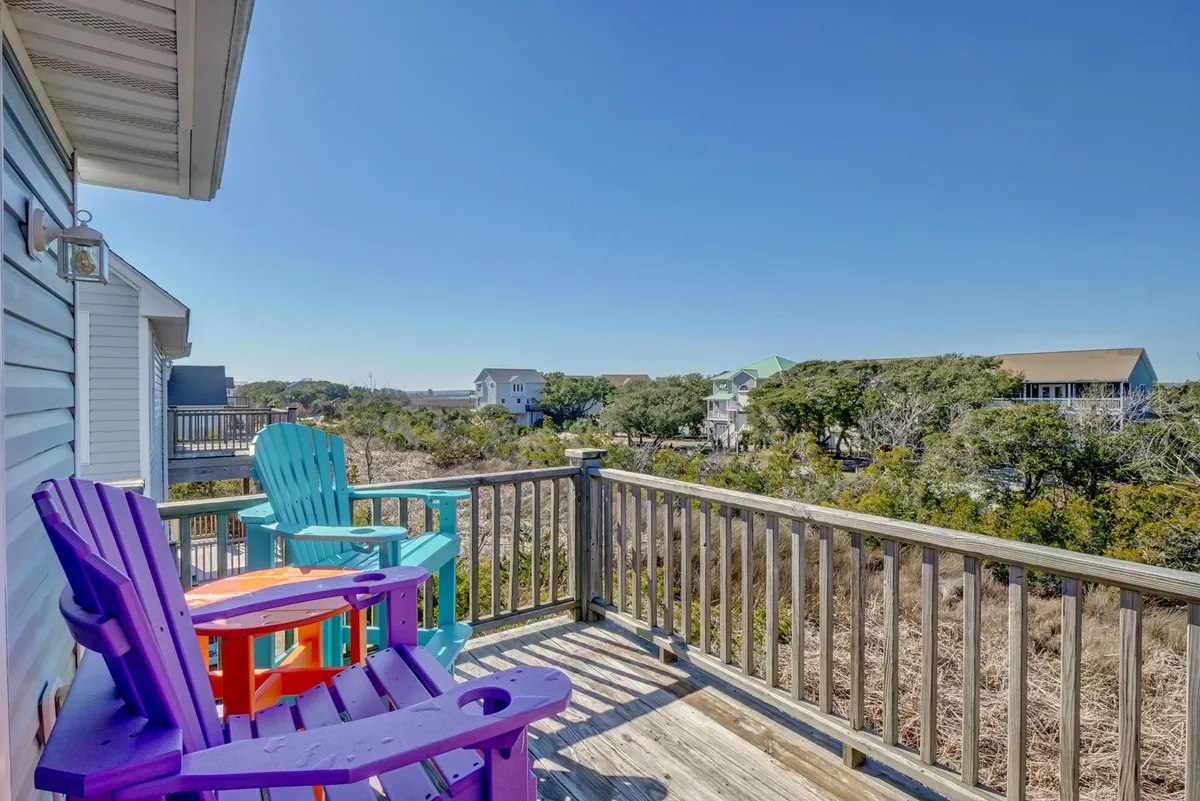 A balcony with colorful chairs overlooks a natural landscape, offering a serene vantage point for relaxing, reading, or socializing in the open air. The setting exudes leisure and connection to the outdoors, perfect for unwinding after a busy day of activities.
