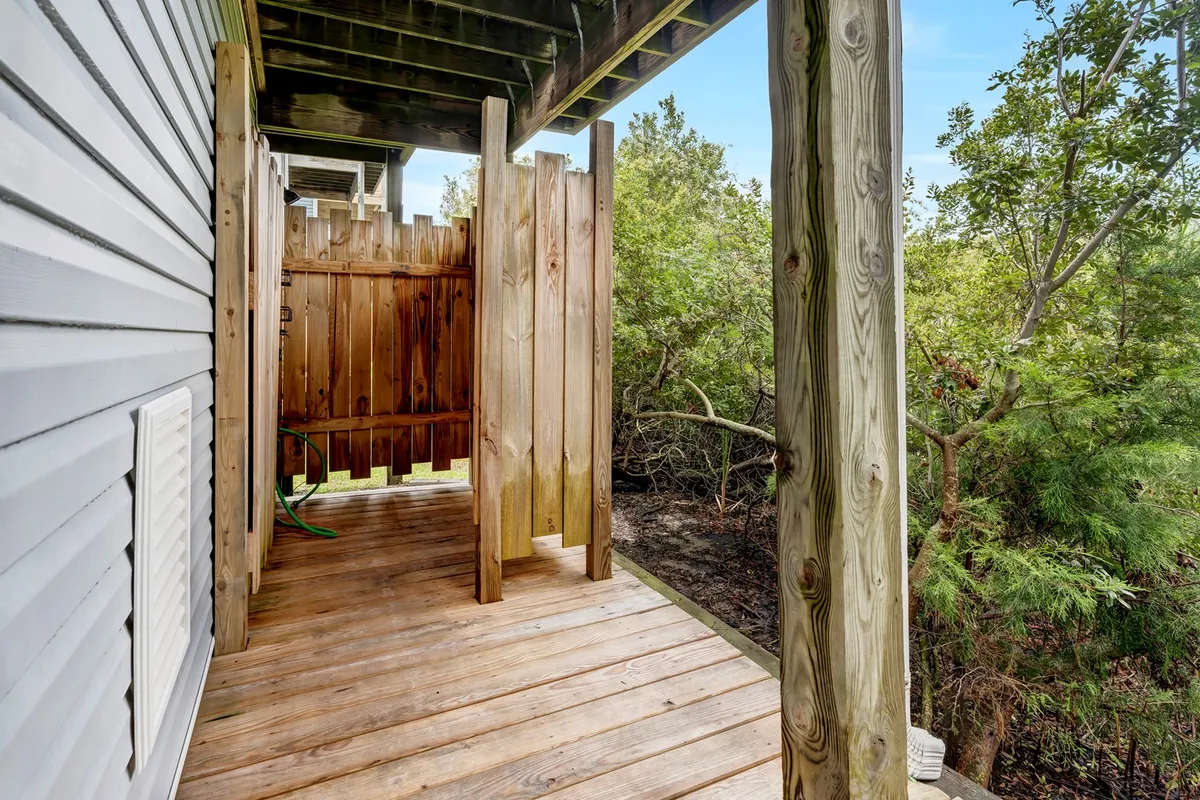 A private wooden deck bordered by a fence and surrounded by greenery, offering an intimate space to unwind. The deck provides a serene spot to read, relax, or enjoy a drink in the fresh air, highlighting the home’s connection to its natural setting and outdoor living possibilities.